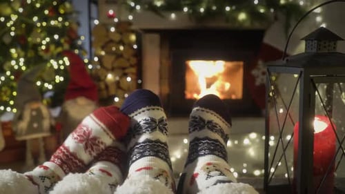 Couple Enjoying By Fireplace and Warming Up Their Feet in Woolen Socks with Christmas Tree and