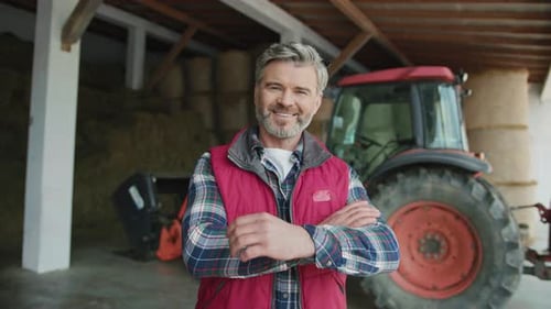 Confident Farmer Smiling in a Barn with Tractor