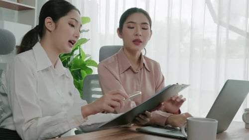 Two Young Enthusiastic Businesswoman Working Together in the Office Workspace