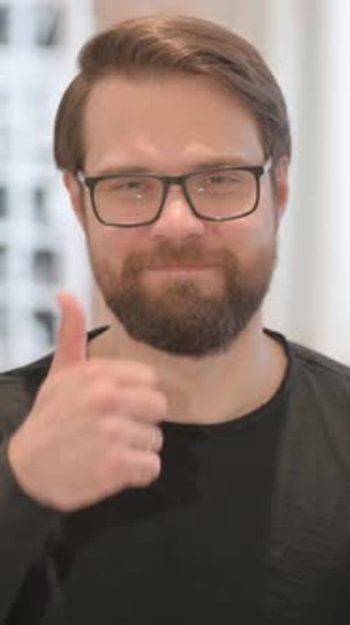 Man wearing glasses gives a thumbs up gesture