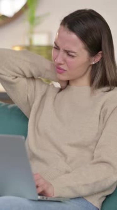 Woman Massaging Stiff Neck While Working on Laptop