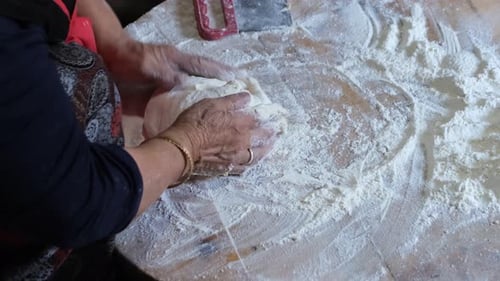 Frauenhände kochen ein türkisches Brot. Brot backen im Dorfhaus