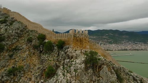 Drone orbit view around the fortress tower on the cliff above the turquoise waters of the Mediterran