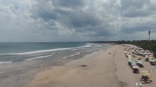 Long Sandy Kuta Beach with Colorful Umbrella Lines and Rolling Surf Bali Island