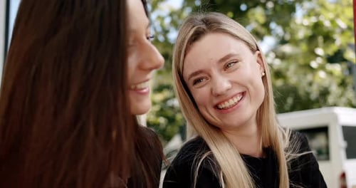 Young Women with Coffee Chatting on Street