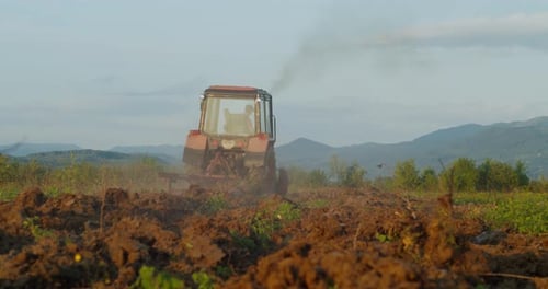 Landwirt auf sowjetischem Traktor, der Land mit einer Stachelzahnegge bewirtschaftet