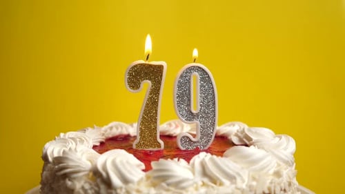 79. A candle in the form of the number 79, stuck in a holiday cake, is blown out. Celebrating a birt
