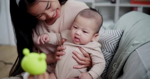 Loving Mother Holds Baby Chewing on Toy at Home