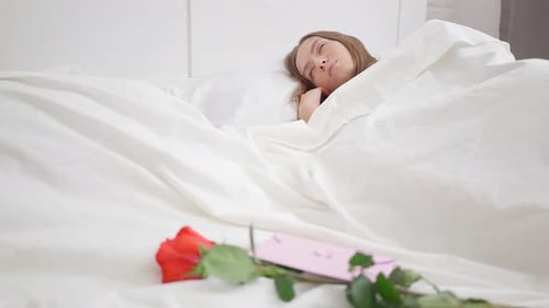 Smiling Woman Wakes Up to Rose and Card