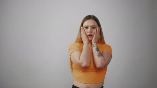 Surprised Young Woman With Hands on Face