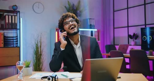 Smiling man office manager in formal wear using phone has conversation during working in office
