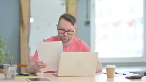 Man Reading Paper Document at Desk in Office
