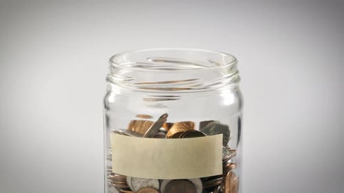 Falling Coins Drop Into Glass Jar for Savings