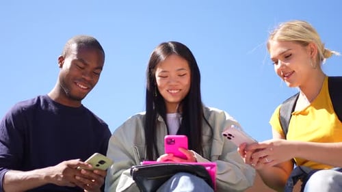 Multiracial Group of Students Using Smartphones Sitting Outside the Campus