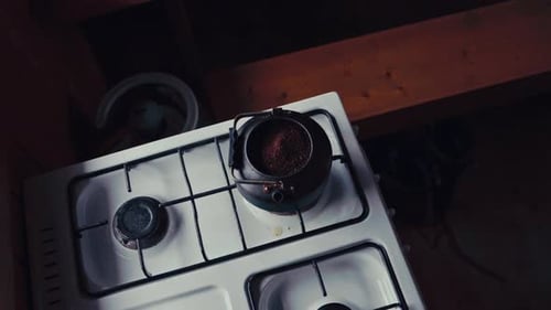 Person Stirring Boiling Drink Over Stove. High Angle Shot