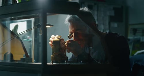 Craftsman Repairs Intricate Antique Clock with Magnifying Glass