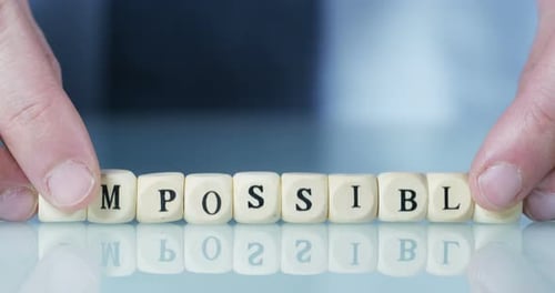 Une main transforme le mot « Impossible » en « Possible » en jetant les lettres. Concept : engagement, b