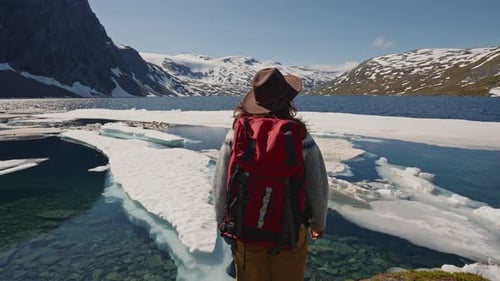 Active Woman with Red Backpack Hiking with Scenic View on Snow Capped Mountain Peaks of Norway