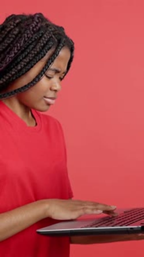 Young Adult Using Laptop on Red Background