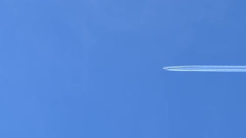 Airplane Contrail in Clear Blue Sky, Right to Left Across Frame.