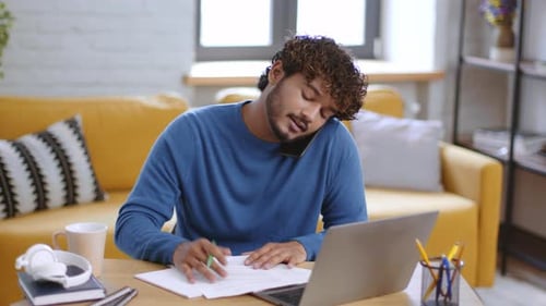 Man Works at Desk, Talks on Phone, Reviews Documents