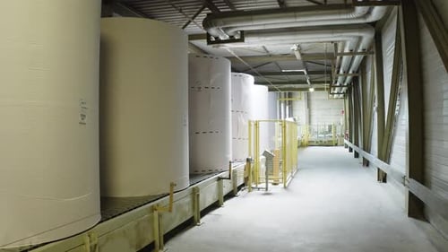 Riesige Papierrollen, die in einer Fabrik zur Herstellung von Papiertüchern in Frankreich über ein Förderband transportiert werden.