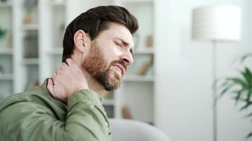 Man Rubbing His Neck in Pain Indoors