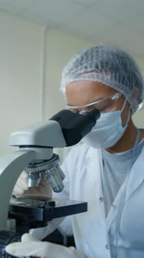 Focused Scientist Looking Through Microscope in the Lab