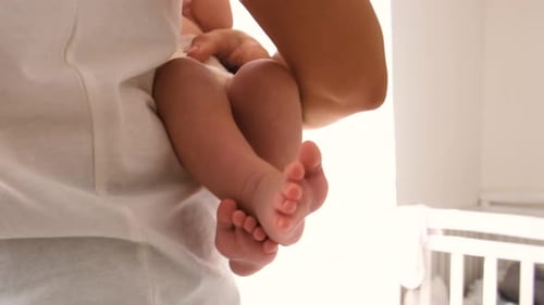 Mother Holding Newborn Infant in Bright Home