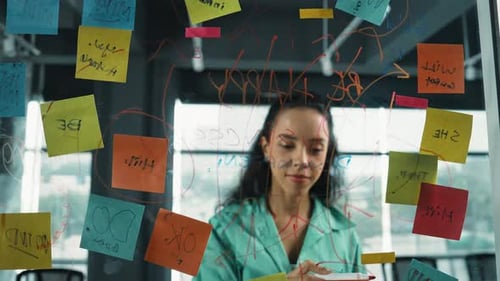 Woman Brainstorming Ideas in Modern Office Writing on Glass