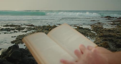Große stürmische Meereswellen rollen am Rocky Beach, während sich der Mann entspannt und ein Buch liest