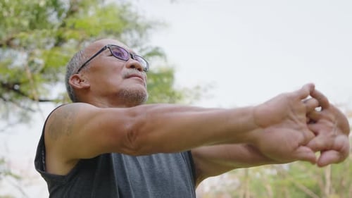 Senior Man Stretching Arms in a Green Park