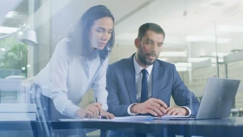 In the Office Female Manager Consults Businessman sitting at His Desk Working on a Laptop, They Agr