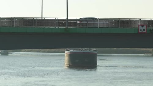 Barges transport crude oil along calm waterways under bridges