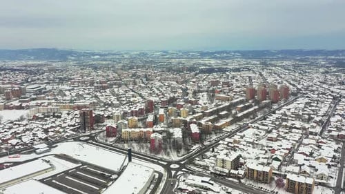 Drone flying above a typical eastern European city covered in snow, fly away