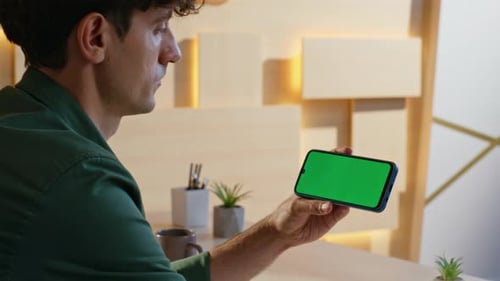 Freelancer Watching Social Media at Green Screen Cellphone in Office Closeup