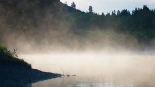 Morning Mist Drifts Across Lake Water In Sunrise Light