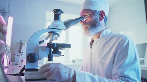 Man Using Microscope in a Blue Lit Lab
