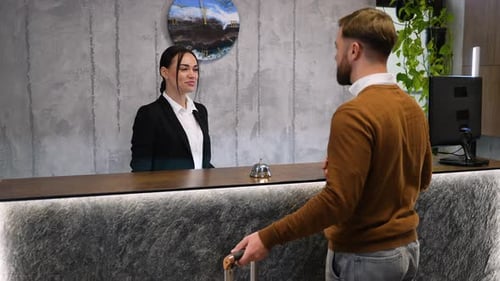 Hotel Receptionist Welcoming a Guest at the Check in Desk