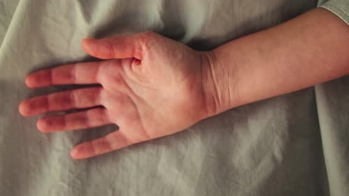 Woman's Hand Making a Fist on a Sheet