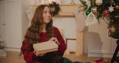 Woman Smiling, Opening Christmas Gift at Home