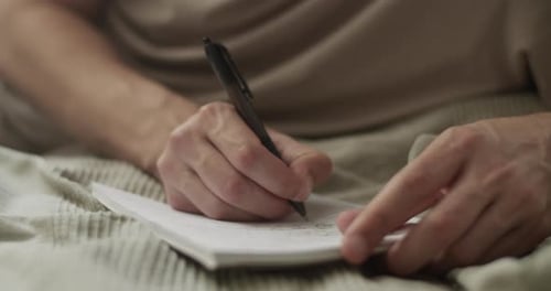Person Writing in Notepad with Pen, Close Up