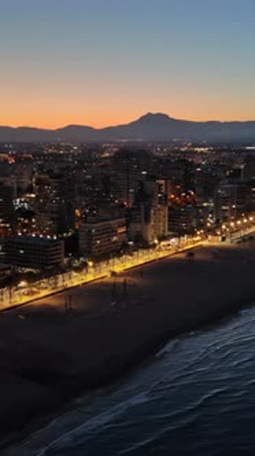 Aerial drone view of the Mediterranean Sea and the Alicante city in Spain at sunset. Vertical