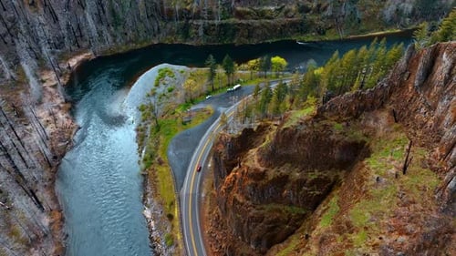 Watching the red car moving quickly by the highway at the waterfront of mountain river.