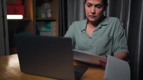 Woman working with Laptop and Documents at Night