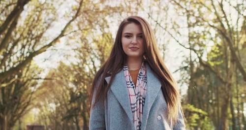 Portrait of Beautiful Young Caucaian Brunette Woman with Long Hair and in Coat Standing in Park