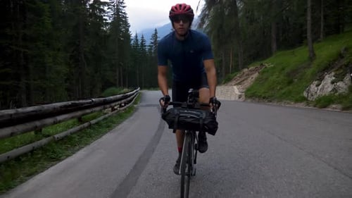 Healthy Male cycling behind a car at high speed in the mountains in the Italian Dolomites in Italy,
