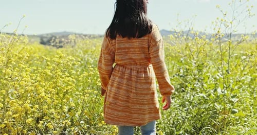 Child, walking and field with flowers in spring, summer or nature in countryside, farm or meadow