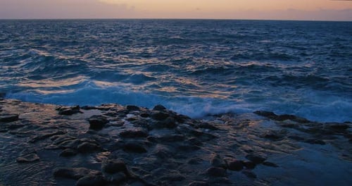Waves splashing on rocky coast at sunrise, cinematic picturesque black volcanic shoreline. Tenerife.