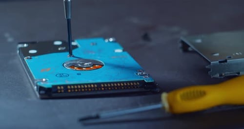 Nahaufnahme einer kleinen Festplatte bei der Reparatur auf einem Tisch eine kleine Schraube wird durch eine kleine Schraube angezogen
